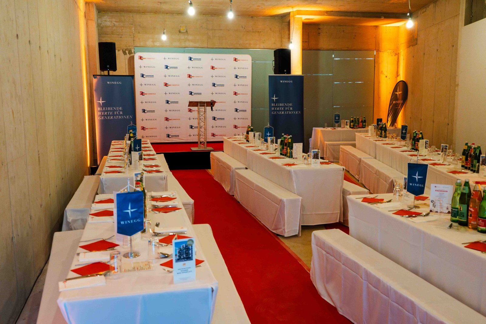 Stilvoll vorbereiteter Eventraum mit Bühne, Rednerpult, Eventtechnik und elegant gedeckten Tischen bei der Gleichenfeier